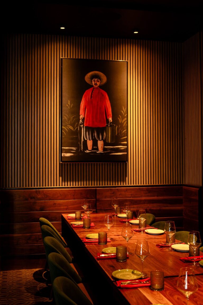 A long table set for dinner beneath a framed portrait