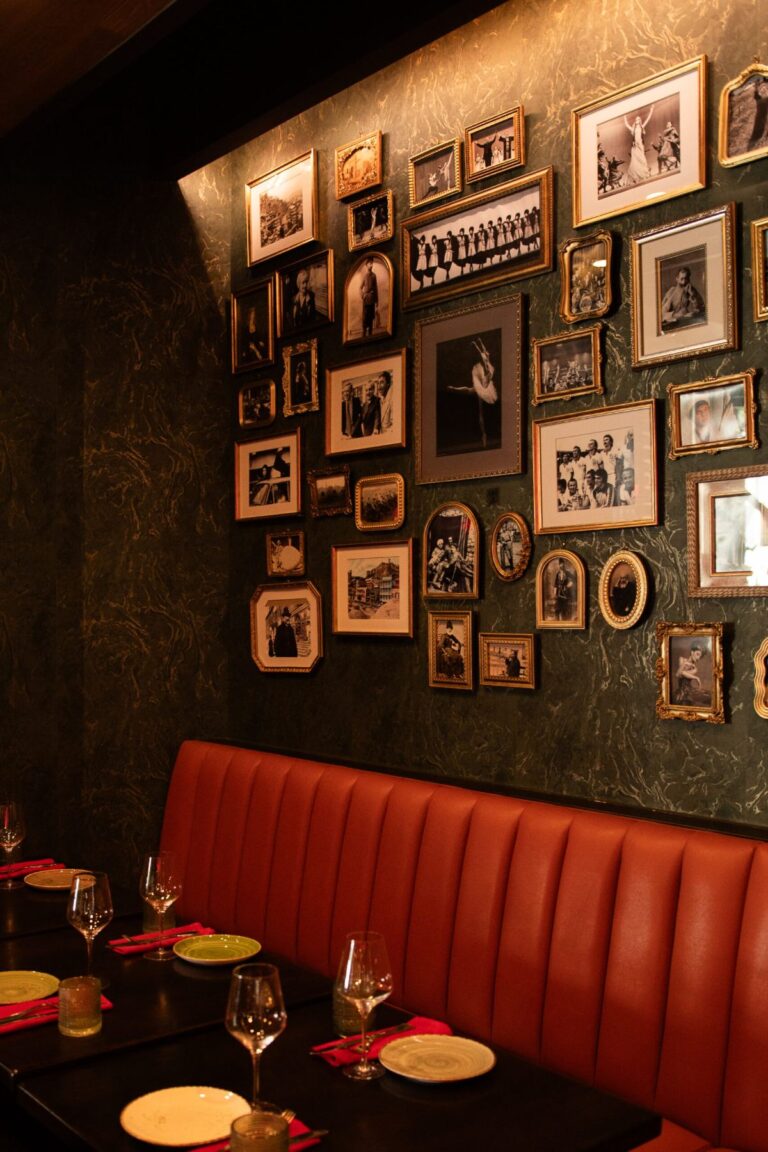 A wall of framed photographs above an orange banquette