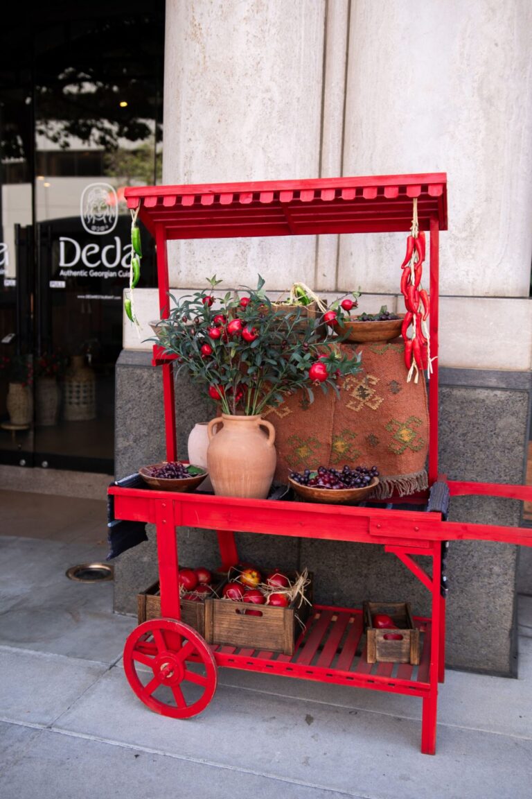 A red flower and produce cart outside the restaurant entrance
