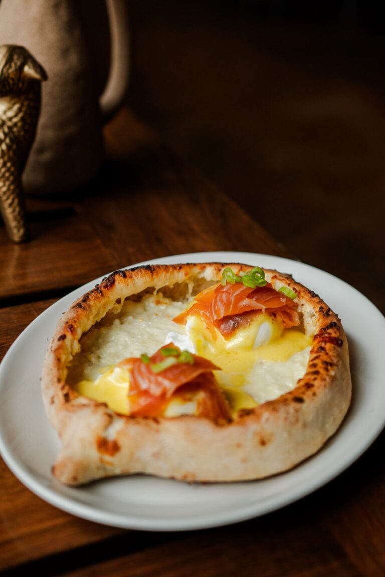 Khachapuri topped with eggs on a white plate